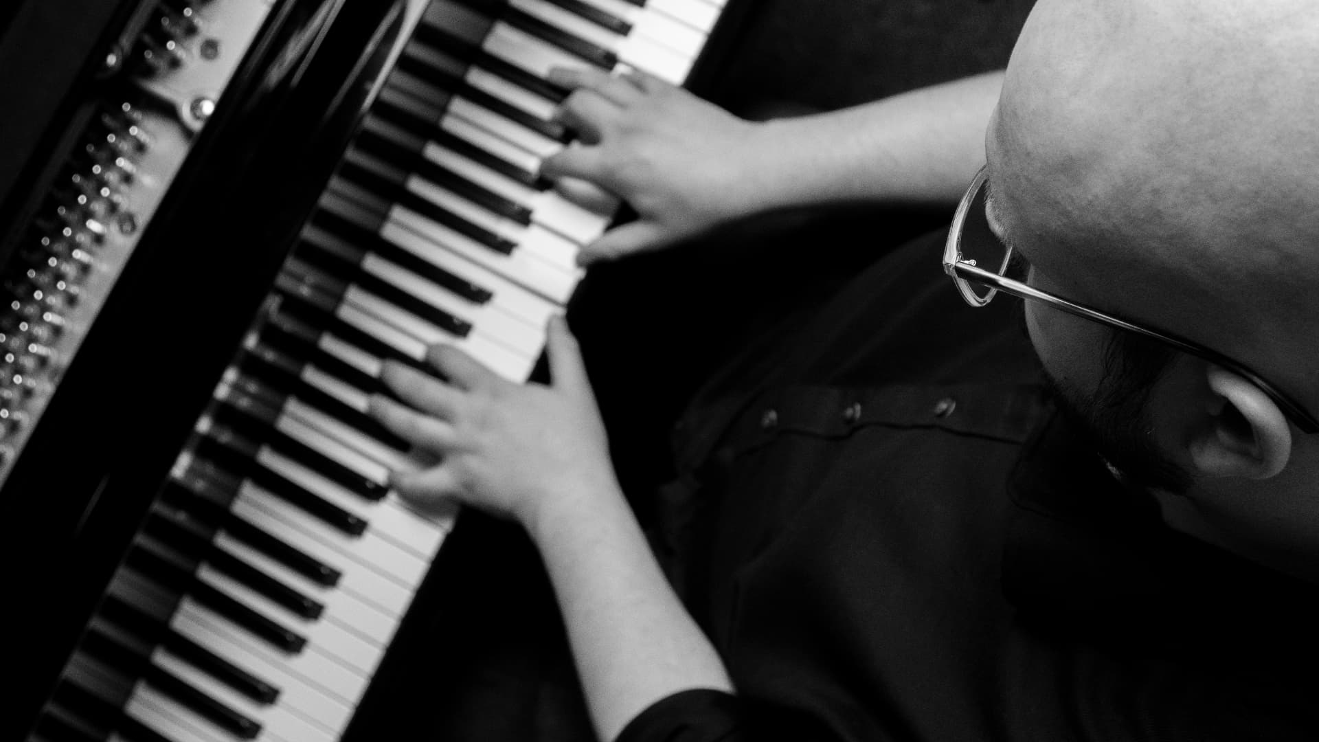 Jeffrey Carabelos playing grand piano, shot from above in black and white